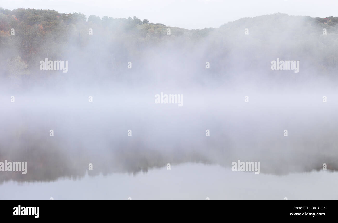 Fallen Sie am frühen Morgen Naturkulisse der Nebel steigt über die Pfeilspitze See enthüllt herbstlichen Wald hinter. Ontario, Kanada. Stockfoto