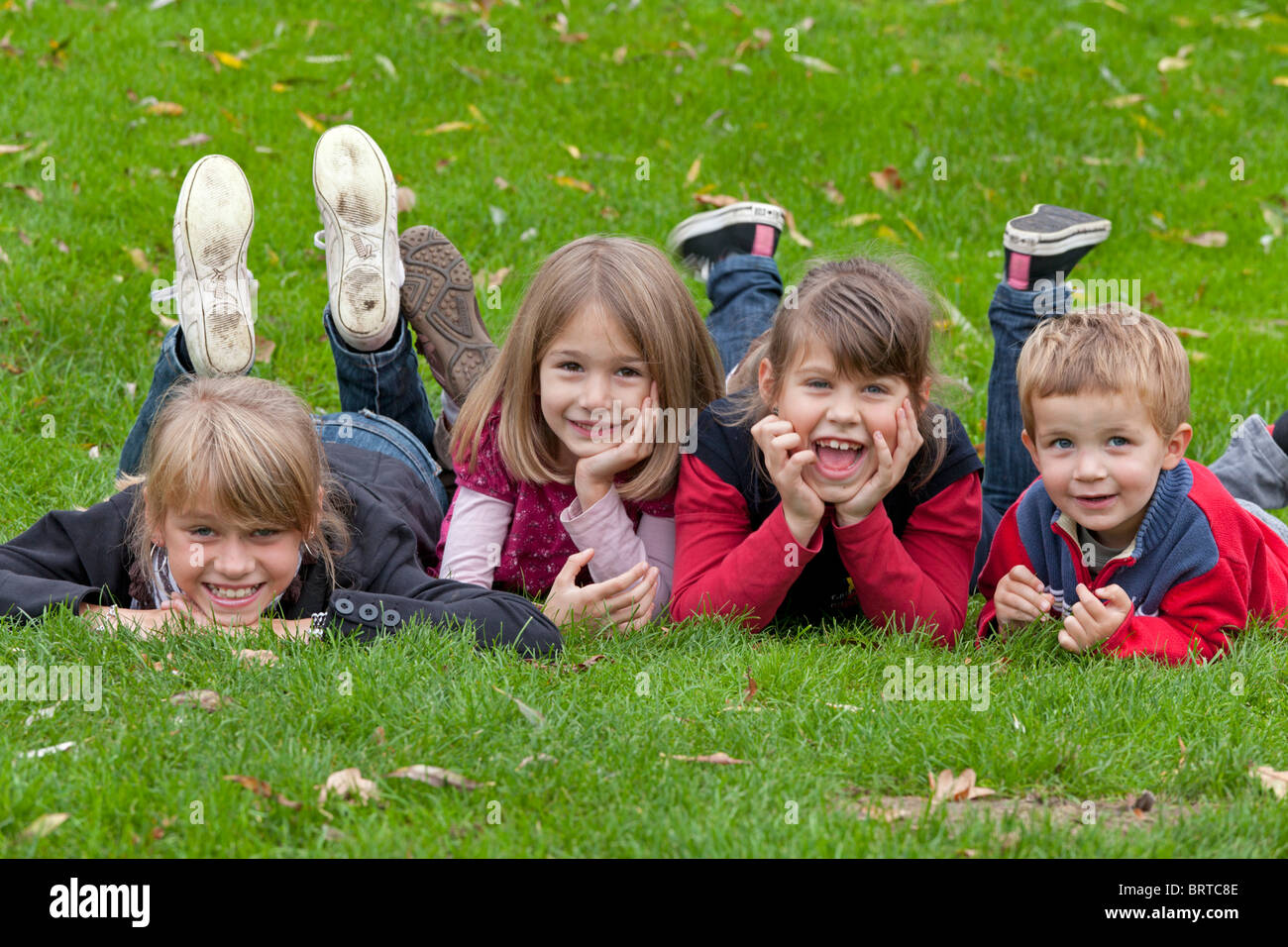 Porträt von vier kleinen Kindern liegen auf einer Wiese in die Kamera schaut Stockfoto