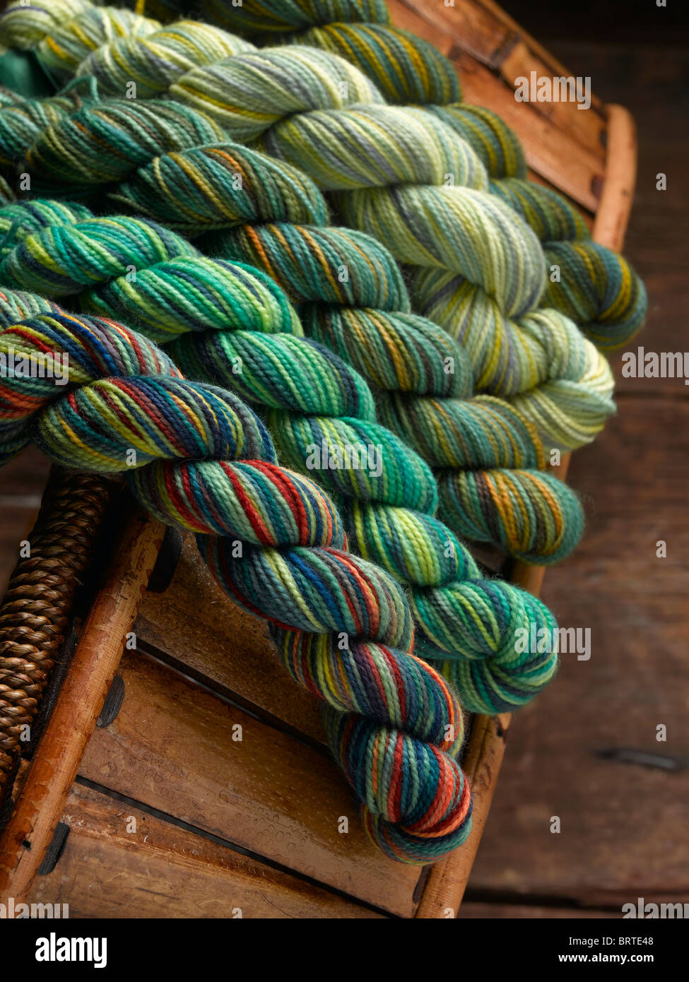 Bunte Knäuel von Hand gefärbtes Garn stricken aus rustikalem Holz Korb verschütten. Stockfoto