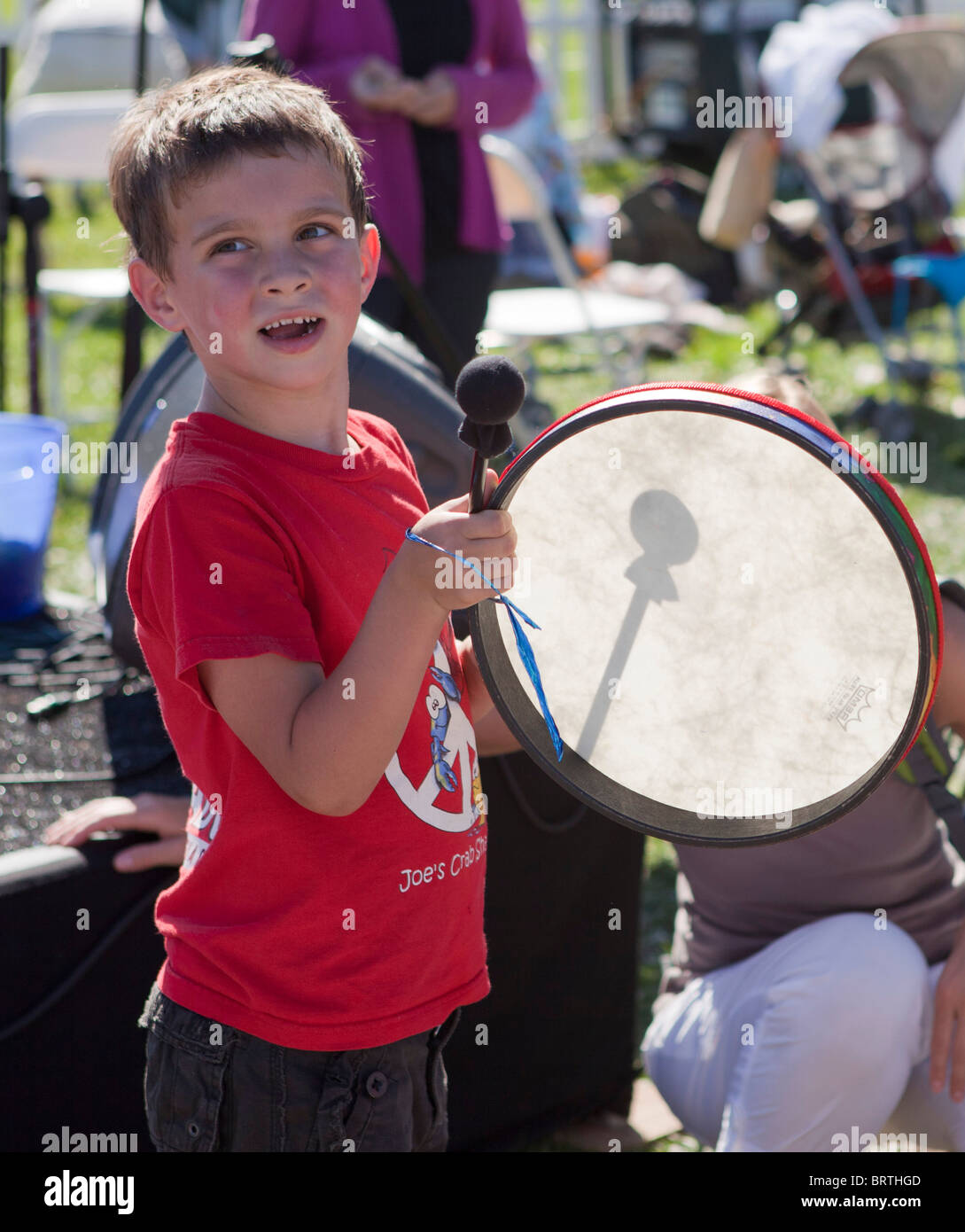 Ein kleiner Junge knallt auf einer Trommel bei einem Outdoor-Musik-festival Stockfoto