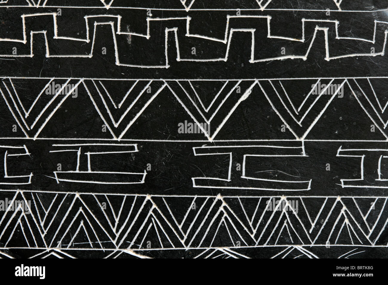 Detail eines geschnitzten Speckstein-Objekts mit abstrakten Mustern in weiß auf schwarz Stockfoto