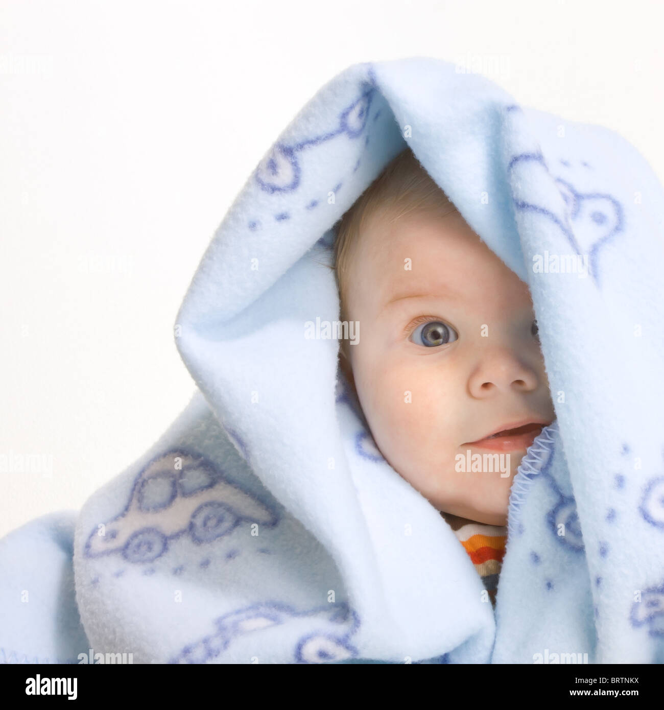 Expressive niedlichen kleinen Jungen fallenden weichen blauen Decke isoliert auf weißem Hintergrund. Stockfoto