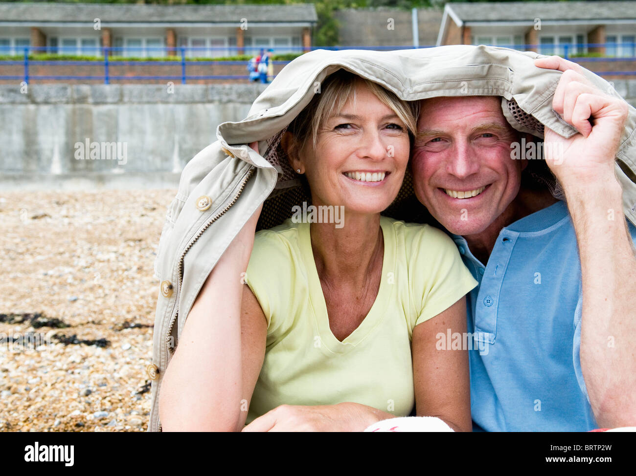 Senioren-Schutz unter Mantel am Strand Stockfoto