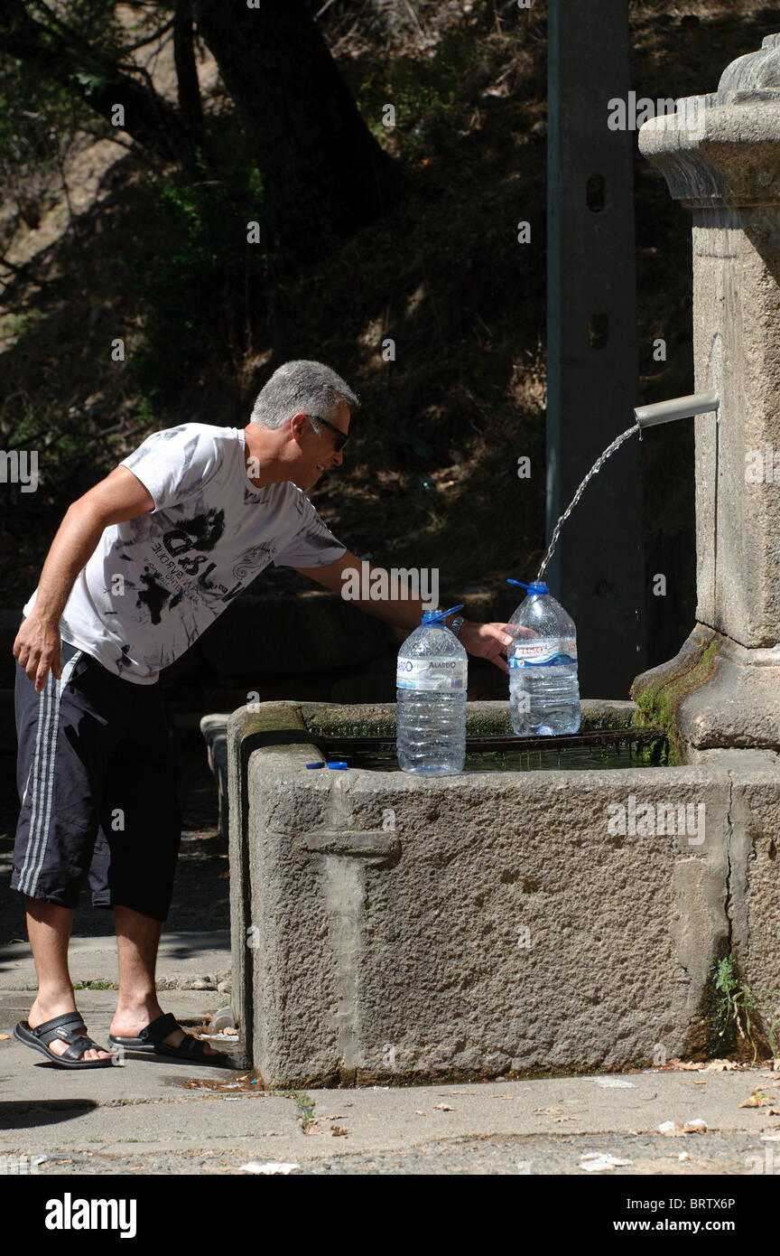 Man füllt Wasser in Flaschen an einem öffentlichen Brunnen Stockfoto