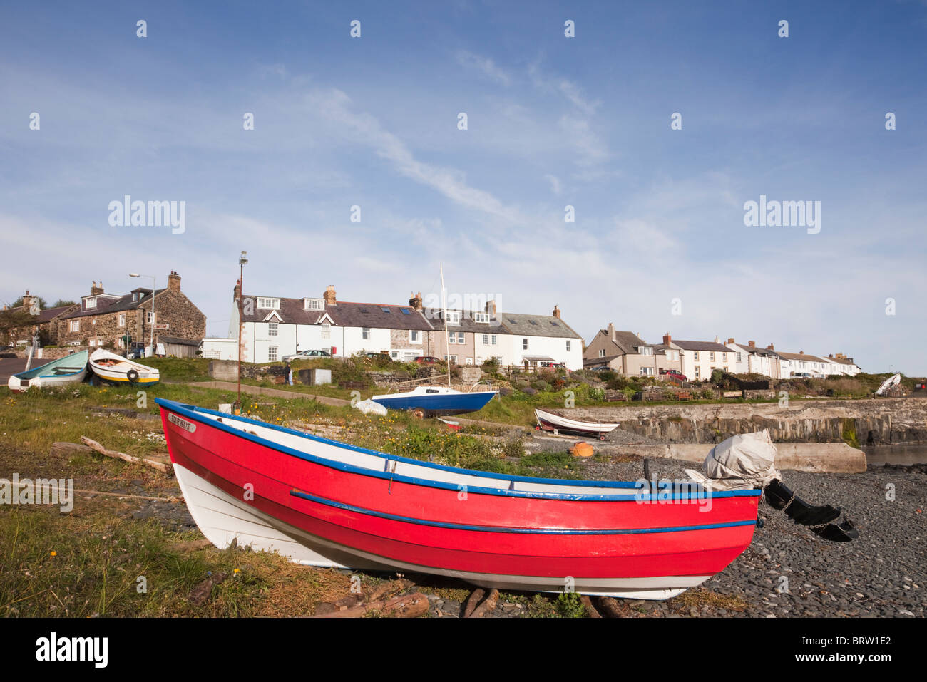 Rotes Boot an der Küste am Hafen in einem kleinen Fischerdorf an der nordöstlichen Küste Northumbrias. Craster, Northumberland, England, Großbritannien. Stockfoto