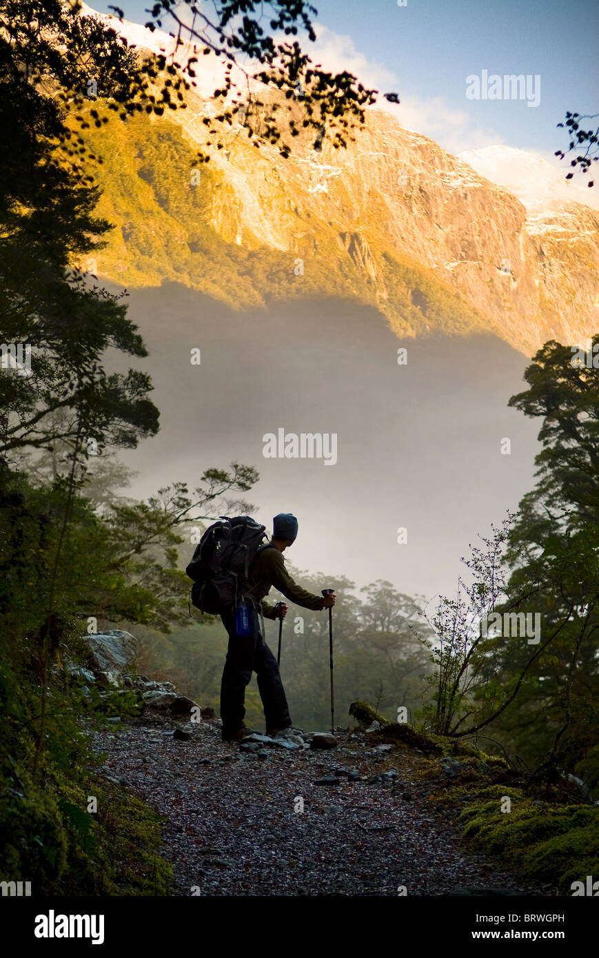 Ein Wanderer hält für eine Rast an einer Lichtung beim Aufstieg in die Berge Stockfoto