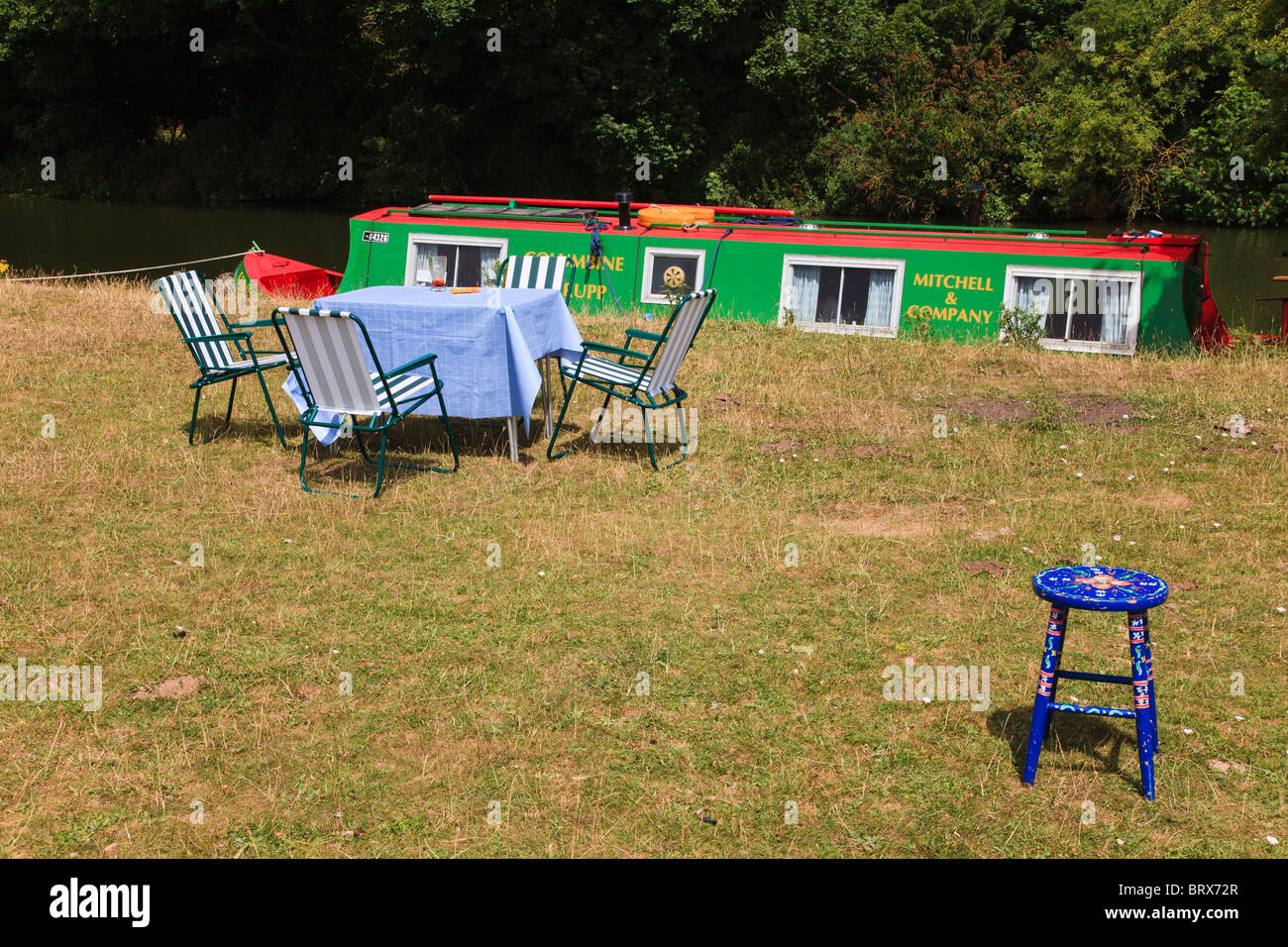 Picknick-Tisch und Stühlen mit einem blauen Blume bemalte Hocker, stehen mit einem schmalen Boot auf der Themse am Godstow, Oxford, UK Stockfoto