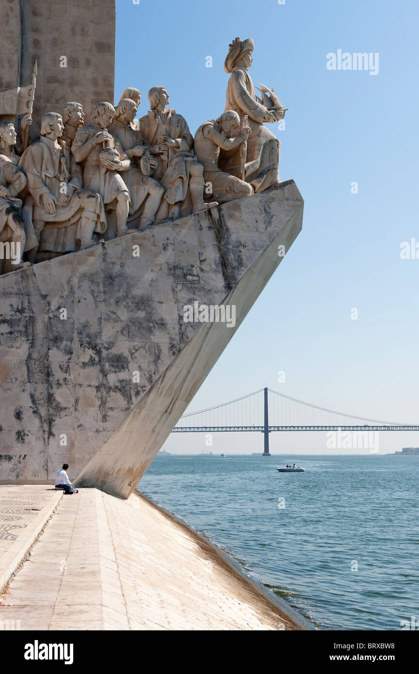 Ein einsamer Tourist in den Schatten gestellt durch das Denkmal der Entdeckungen auf Lissabons Belem waterfront Stockfoto