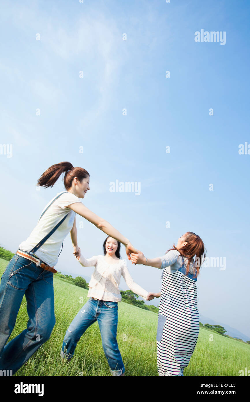 Junge Frauen halten sich an den Händen und laufen im Kreis Stockfoto