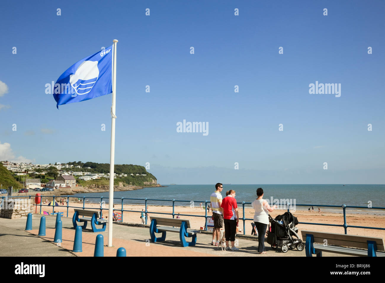 Blaue Flagge an der Strandpromenade mit Blick auf den Strand in walisischen Küstenort Benllech, Isle of Anglesey, North Wales, UK, Großbritannien fliegen Stockfoto