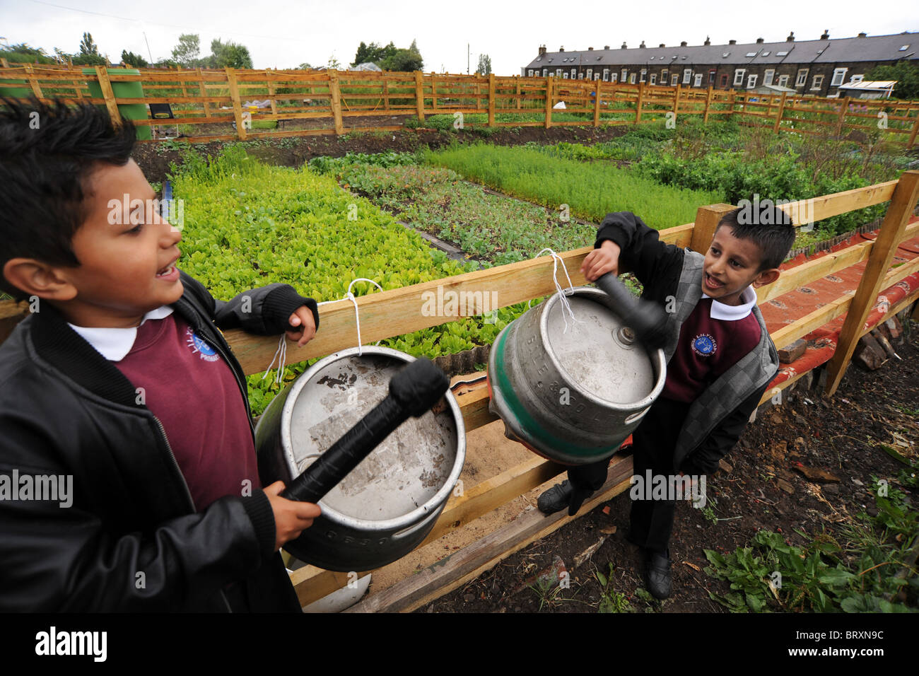 Kinder spielen Trommeln aus alte Bierfässer während einem Besuch in lokalen Kleingärten, Bradford, West Yorkshire Stockfoto