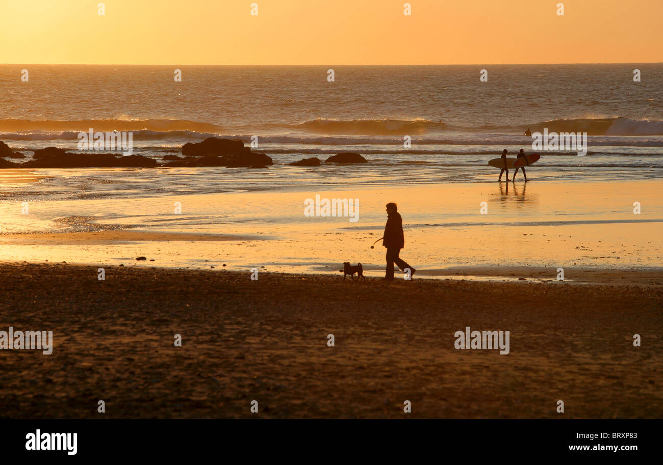 Surfer und Dogwalker an Porthtowan Strand bei Sonnenuntergang, North Cornwall Coast, England, UK. Stockfoto