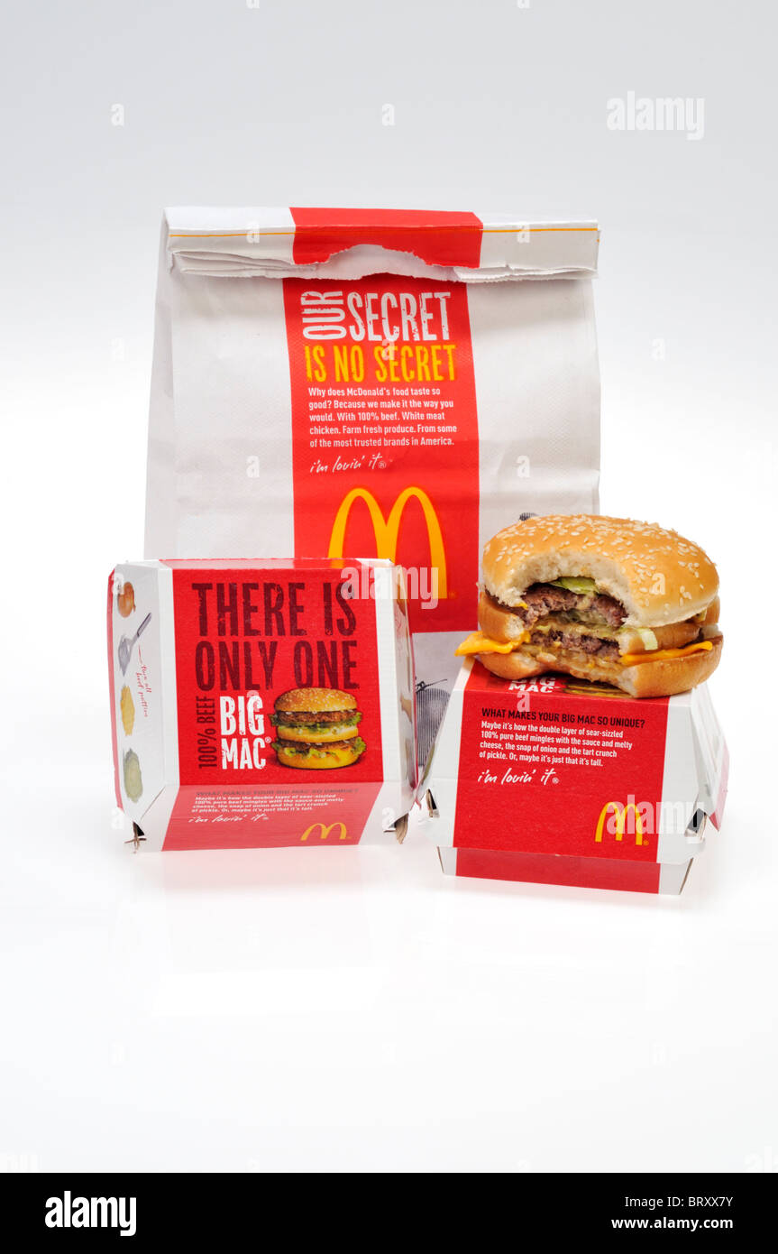 McDonald's-Tasche mit einem Big Mac, das einen Bissen aus ihm heraus auf weißem Hintergrund ausgeschnitten hat. Stockfoto