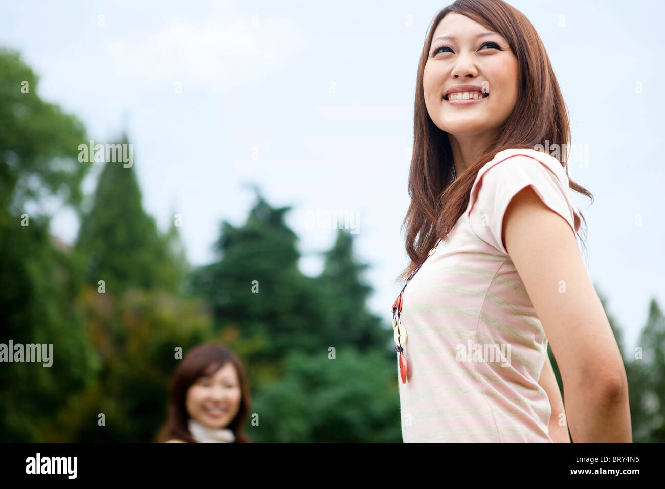 Zwei junge Frauen lächelnd und Wegsehen Stockfoto