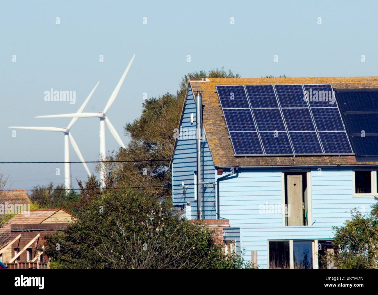 Windkraftanlagen hinter einem Haus mit Solarzellen recycelt Haus Camber Roggen East Sussex Stockfoto