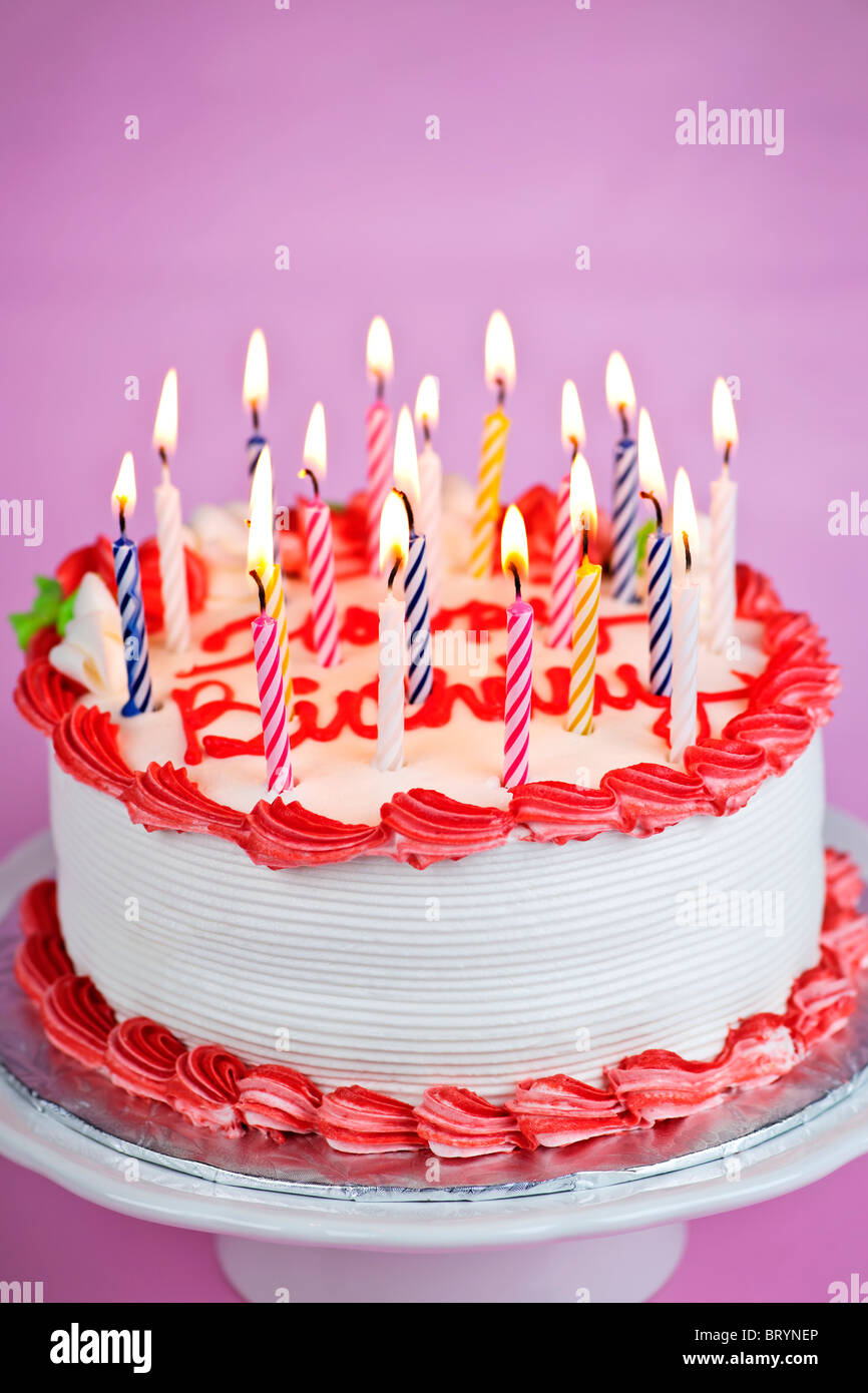 Geburtstagstorte mit brennenden Kerzen und weißem Zuckerguss Stockfoto