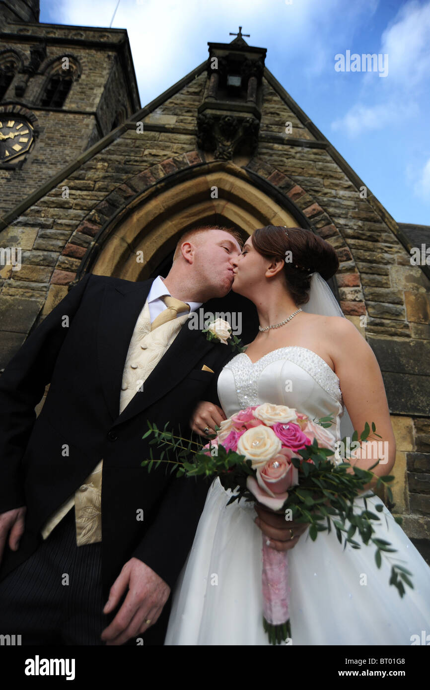 Braut und Bräutigam just married küssen außerhalb der Kirche Stockfoto
