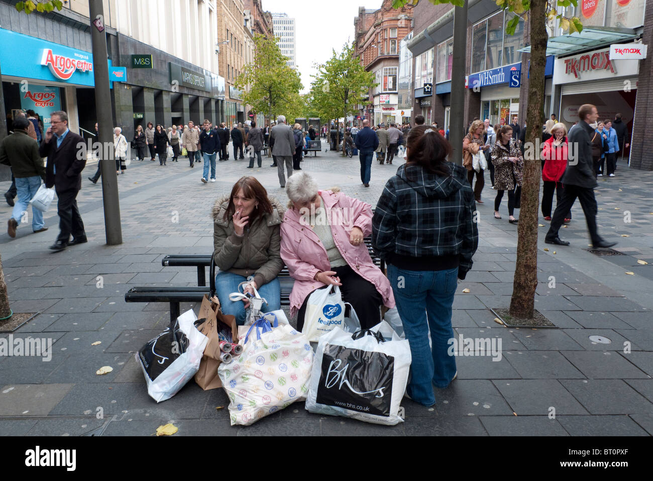 Weibliche Käufer auf der Sauchiehall Street sitzen Rauchen von Zigaretten mit ihren Taschen shopping Glasgow Schottland Großbritannien Stockfoto