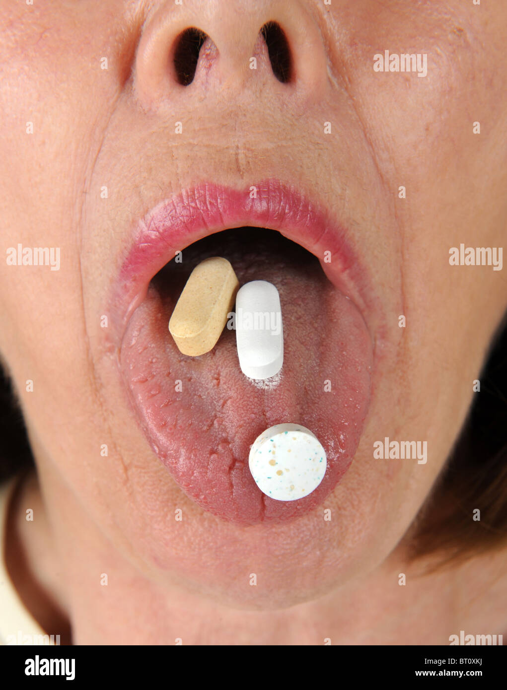 mittlere gealterte Frau mit Vitaminen auf Zunge Stockfoto