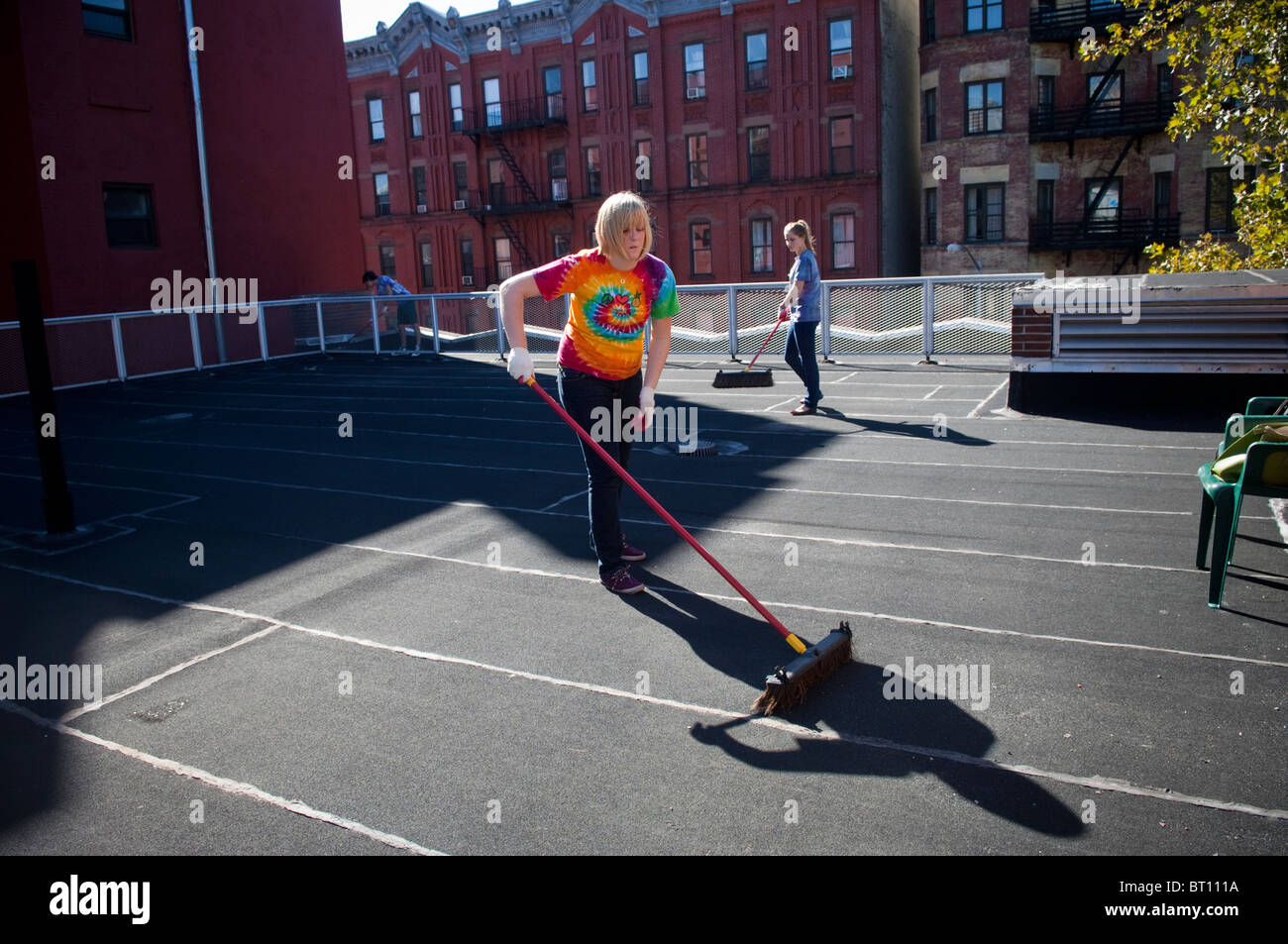 College Student Freiwilligen reinigen Dach vor der Malerei als eine Coolroof in Harlem in New York Stockfoto