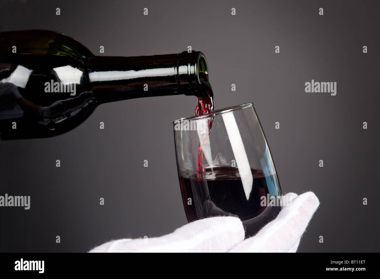 Kellner schenkt ein Glas Rotwein. Bild wurde im Hintergrund sanfte Holzkohle Gradienten zu geben, eine feine, dunkle Stimmung erschossen. Stockfoto