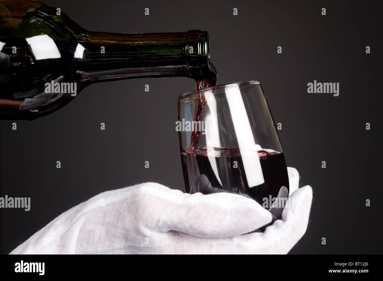Kellner schenkt ein Glas Rotwein. Bild wurde im Hintergrund sanfte Holzkohle Gradienten zu geben, eine feine, dunkle Stimmung erschossen. Stockfoto