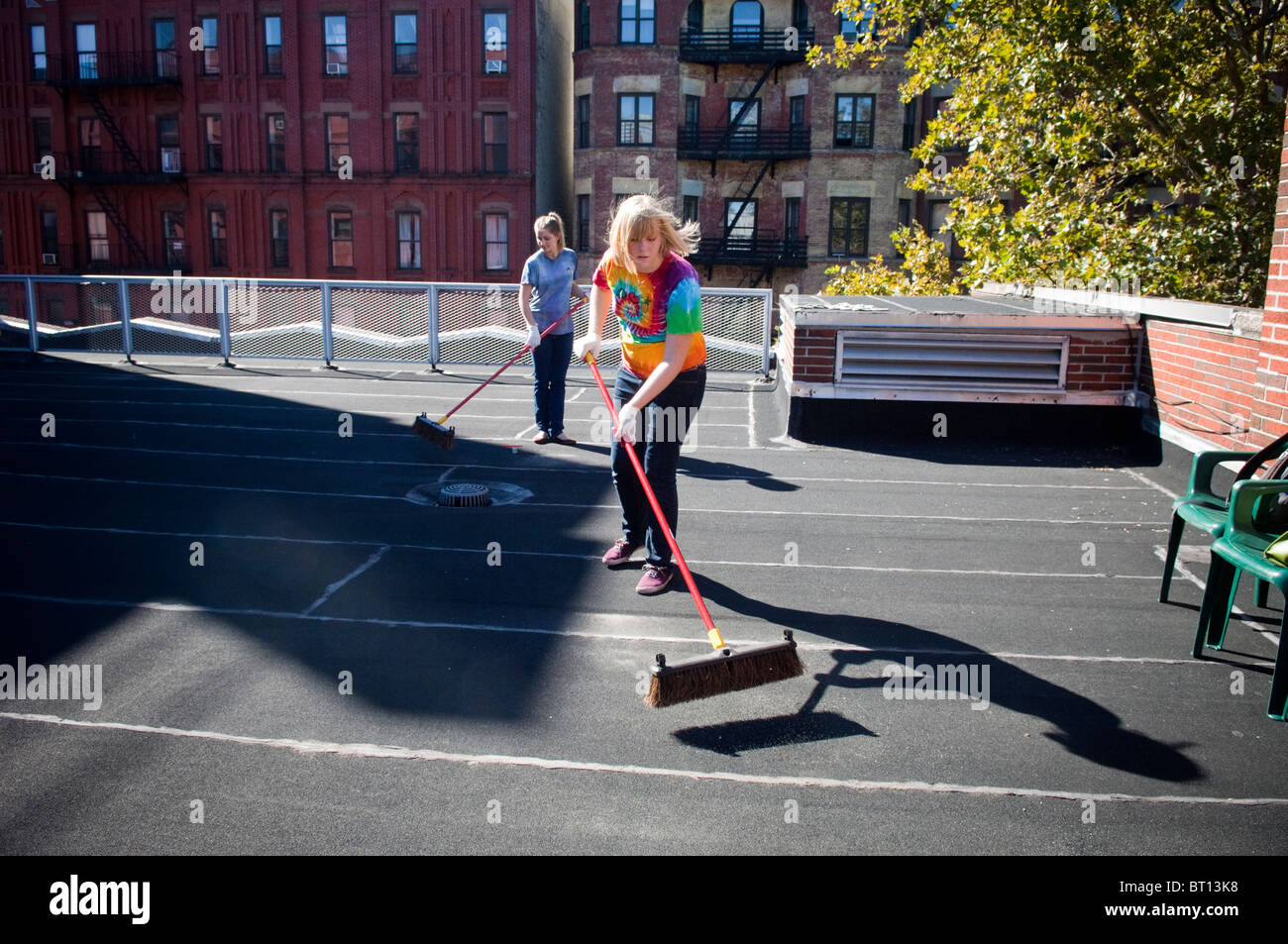 College Student Freiwilligen reinigen Dach vor der Malerei als eine Coolroof in Harlem in New York Stockfoto