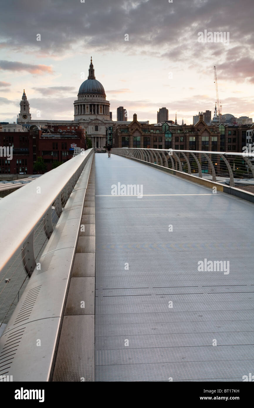 Mann zu Fuß über die Millennium Bridge über die Themse bei Sonnenaufgang mit Blick auf St. Pauls Cathedral, London, Uk Stockfoto