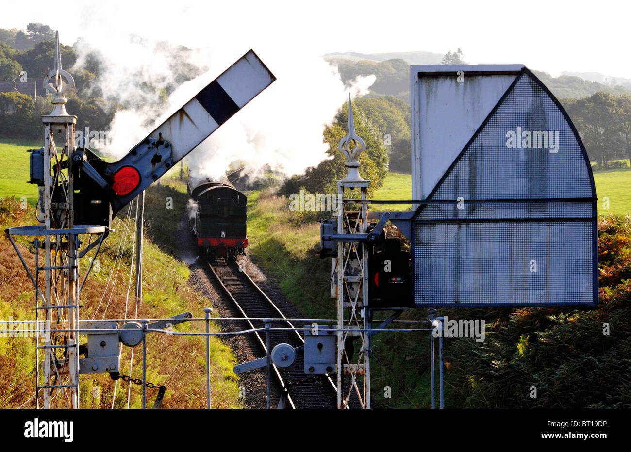 Dampfzug nähert sich eine alte Gantry Signal auf der Bahnstrecke erhaltenen swanage Stockfoto