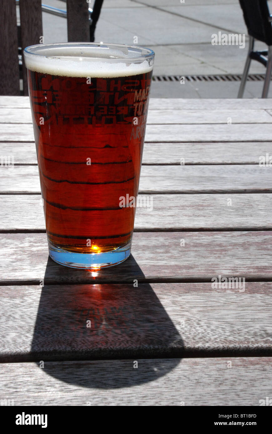 Bier trinken am Holztisch in der Sonne, in Erwartung getroffen auf Wellington Waterfront, New Zealand Stockfoto