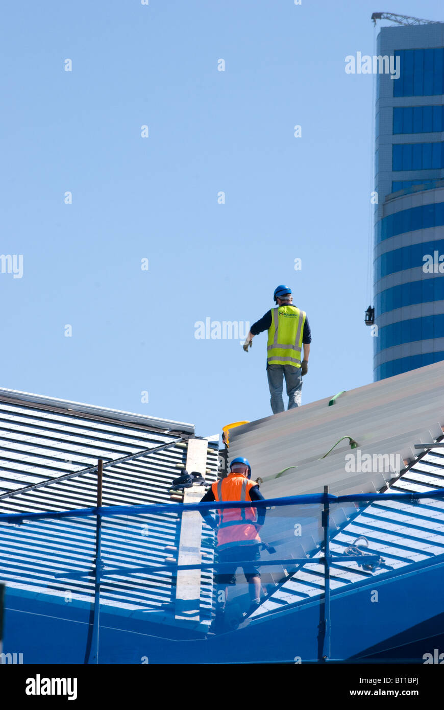 Arbeitnehmer / Bauherren am Dach des Gebäudes site mit blauem Himmel & Towerblock im Hintergrund, Wellington, Neuseeland (Maori Waka /Wharewak Haus) Stockfoto
