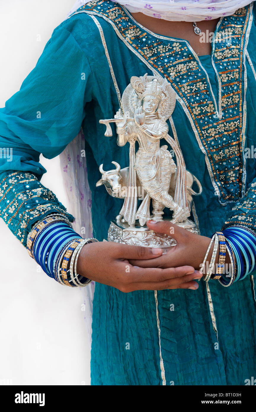 Indische Mädchen hält eine Silber Krishna statue Stockfoto