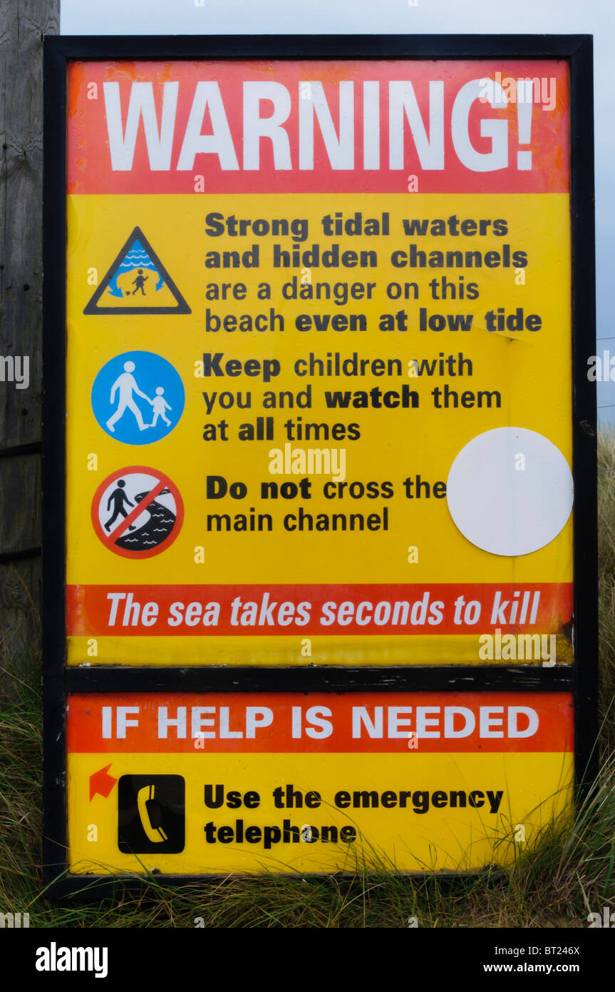 Ein Schild am Eingang zum Brancaster Beach in North Norfolk warnt vor den Gefahren von starken Gezeitenströmungen Stockfoto
