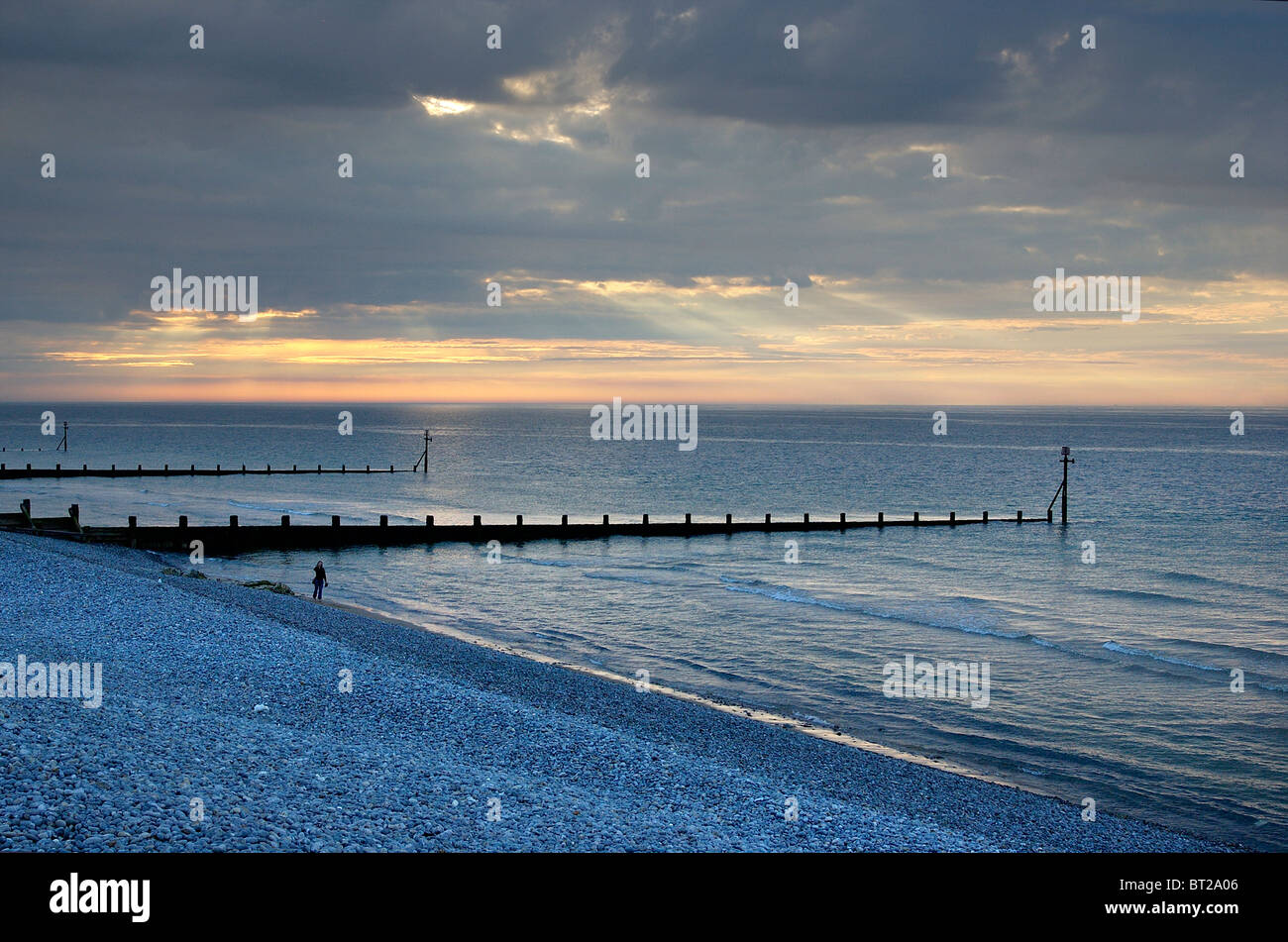 Sonnenuntergang über einem ruhigen Meer in Sheringham, Norfolk mit Silhouette einsame Gestalt am Rand Wassers Stockfoto