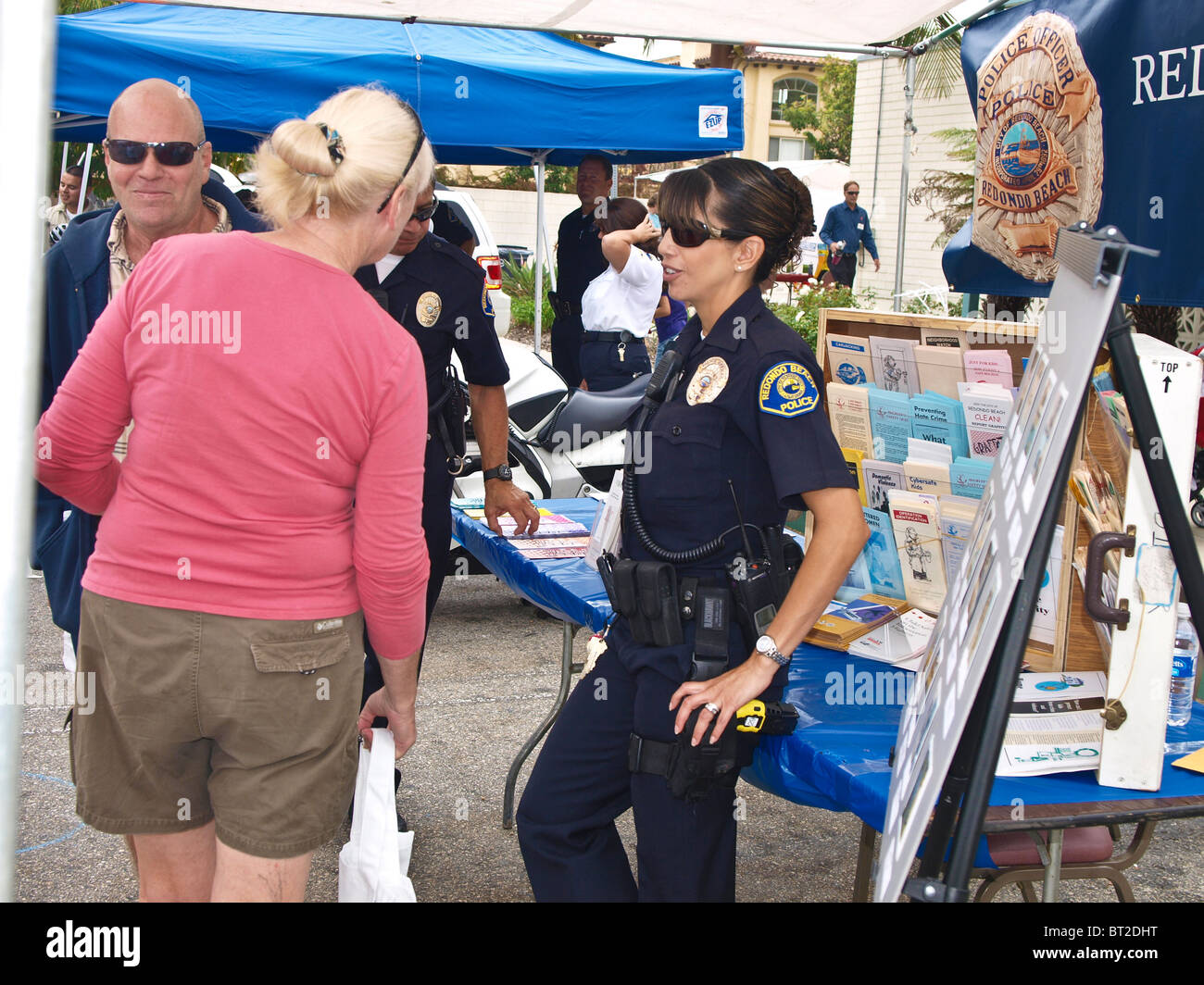 Latino-Polizistin interagiert mit Zivilisten, die Teilnahme an der RBPD Polizei Sicherheit fair. Stockfoto