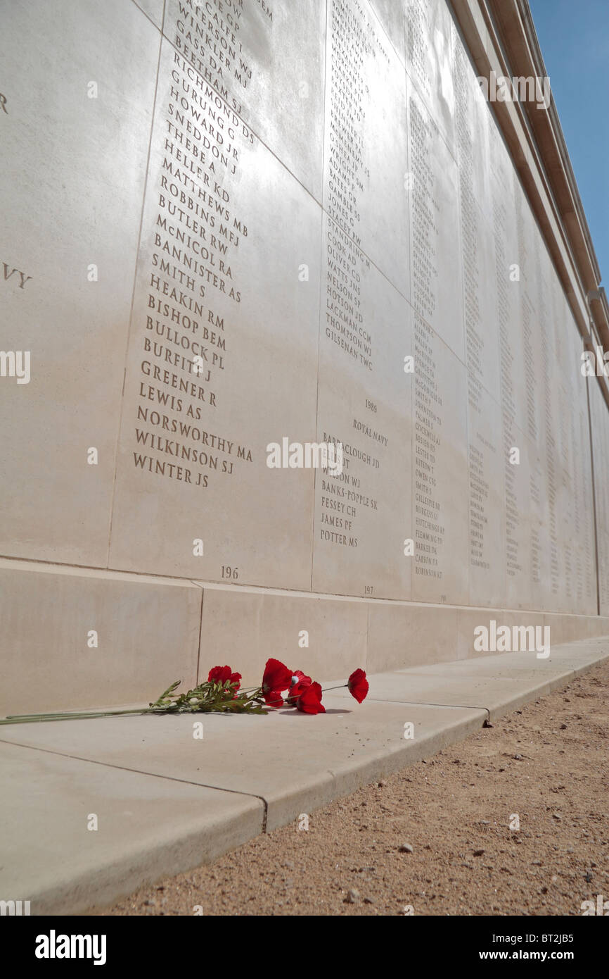 Mohnblumen sitzen unter einem der vielen Mauern der Namen auf der Armed Forces Memorial, National Memorial Arboretum Alrewas, UK. Stockfoto
