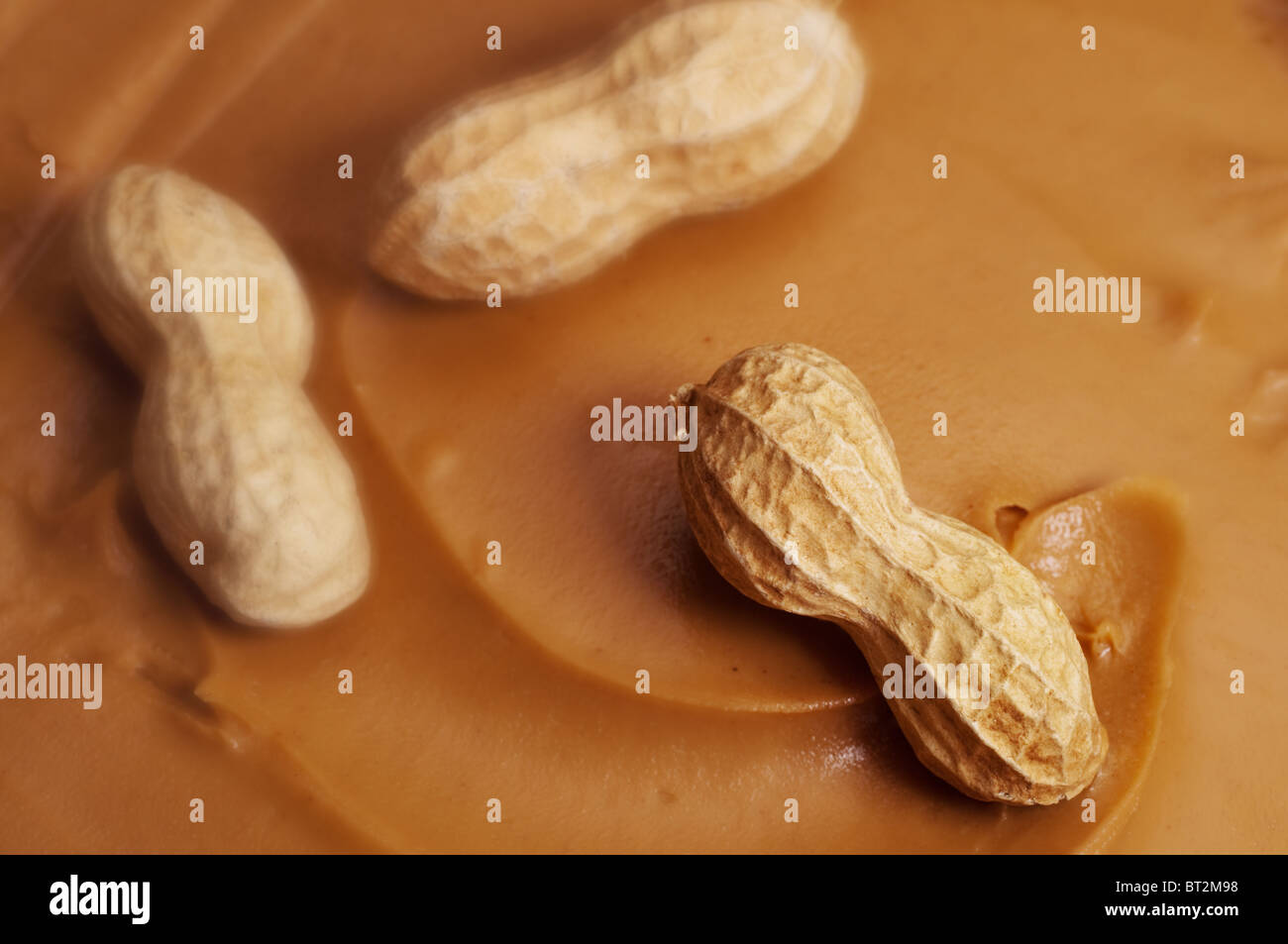 Rohe Erdnüsse im Strudel der cremige Erdnussbutter. Selektiven Fokus auf Erdnuss im Vordergrund. Stockfoto