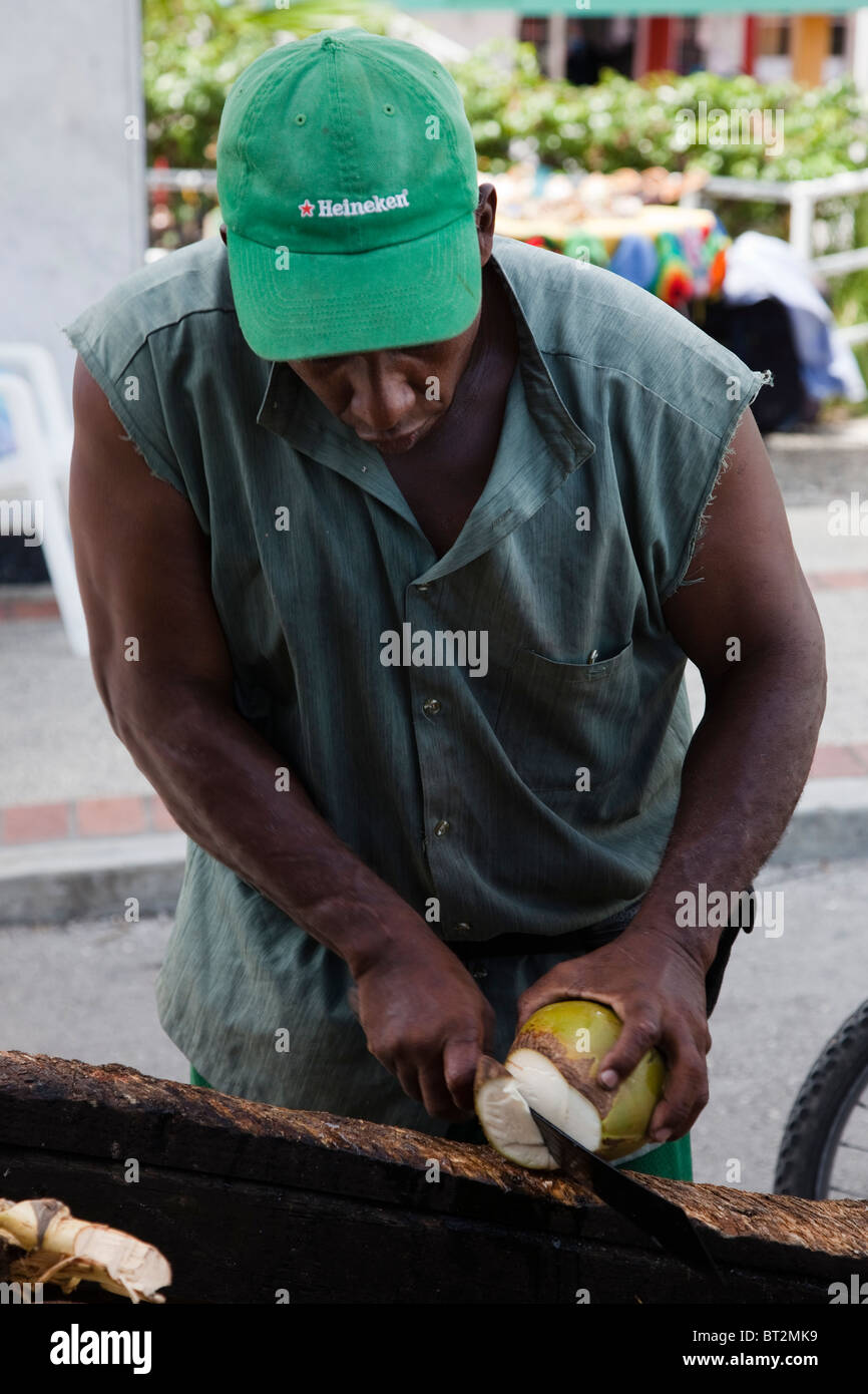 Mann zerschneiden Kokosnüsse zu verkaufen die Milch aus einem Grabhügel, Bridgetown, Barbados Stockfoto