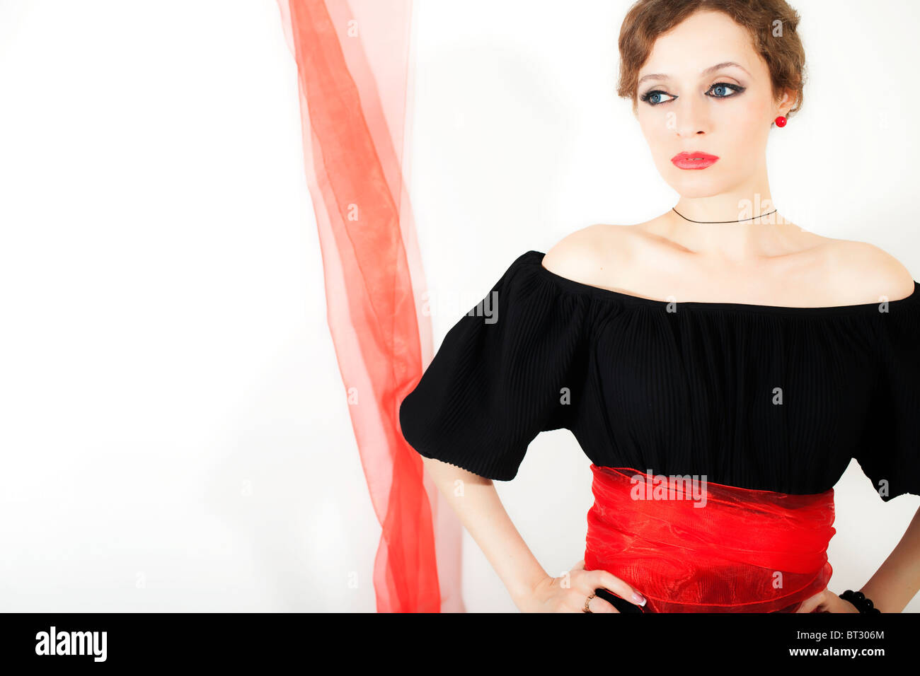 Frau im schwarzen Kleid mit roten Schärpe auf weißem Hintergrund Stockfoto