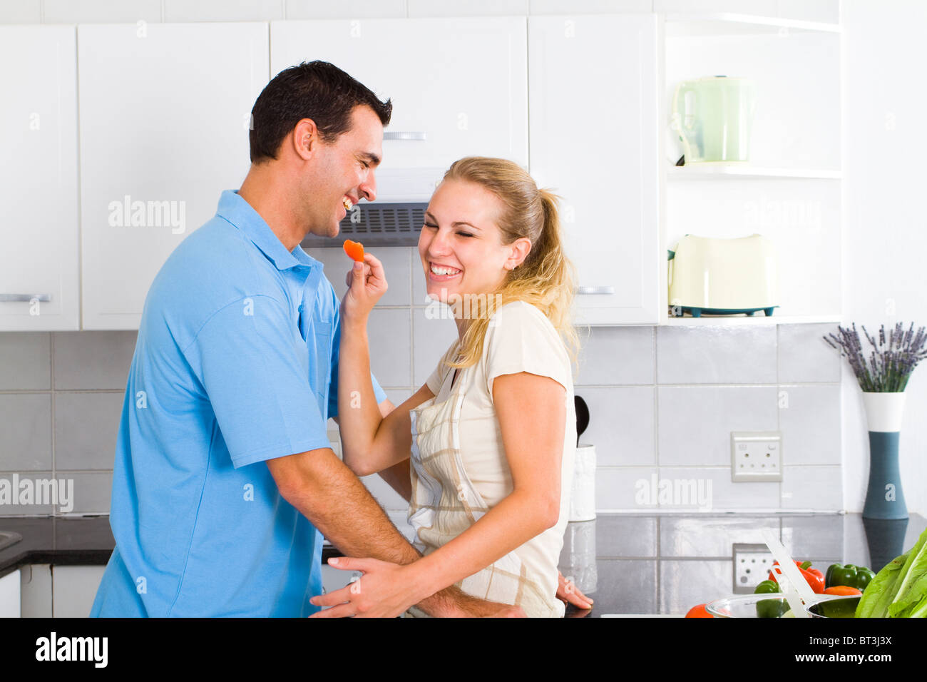 verspielte junge Paar schmeckendes Essen in einer modernen Küche Stockfoto