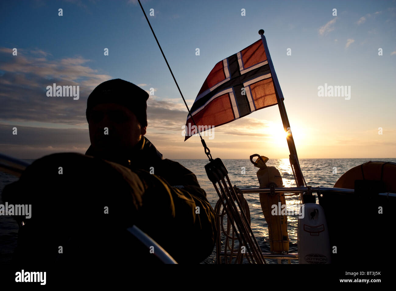 Segeln auf der Nordsee. Sonnenuntergang, Segelboot, Kapitän, norwegische Flagge. Shetland, Großbritannien Stockfoto