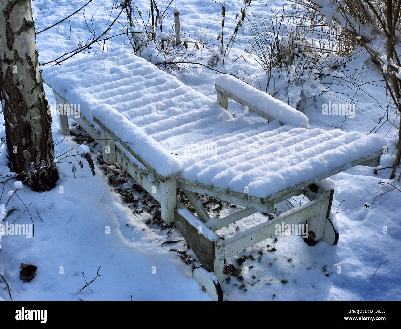 Liegestuhl im winterlichen Garten mit Schnee bedeckt Stockfoto