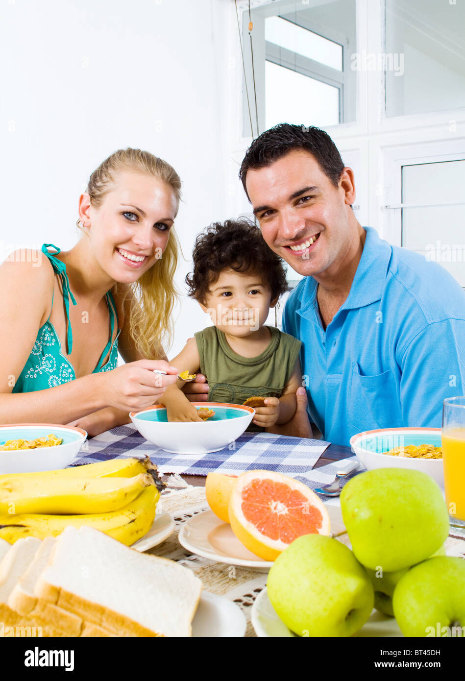 glückliche junge Eltern und Kleinkind Boy am Frühstückstisch Stockfoto
