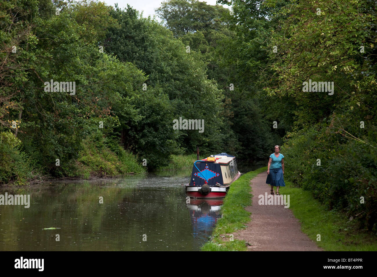 Frau geht vorbei an Kanalboote entlang der Leinpfad des Grand Union Canal bei Hatton in Warwickshire. Stockfoto