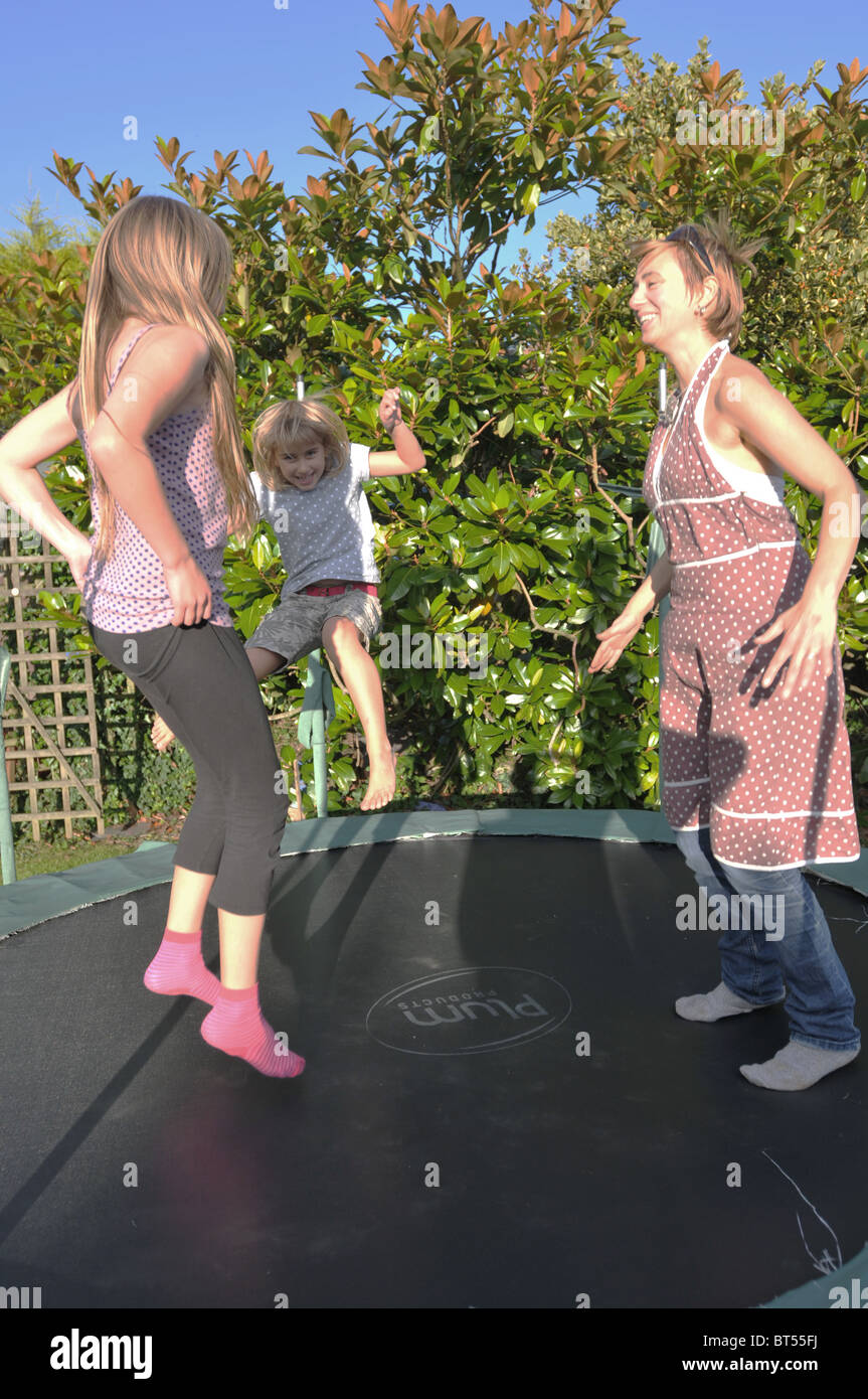 Eine Mutter und ihre 2 Töchter hüpfen auf einem Trampolin Stockfoto