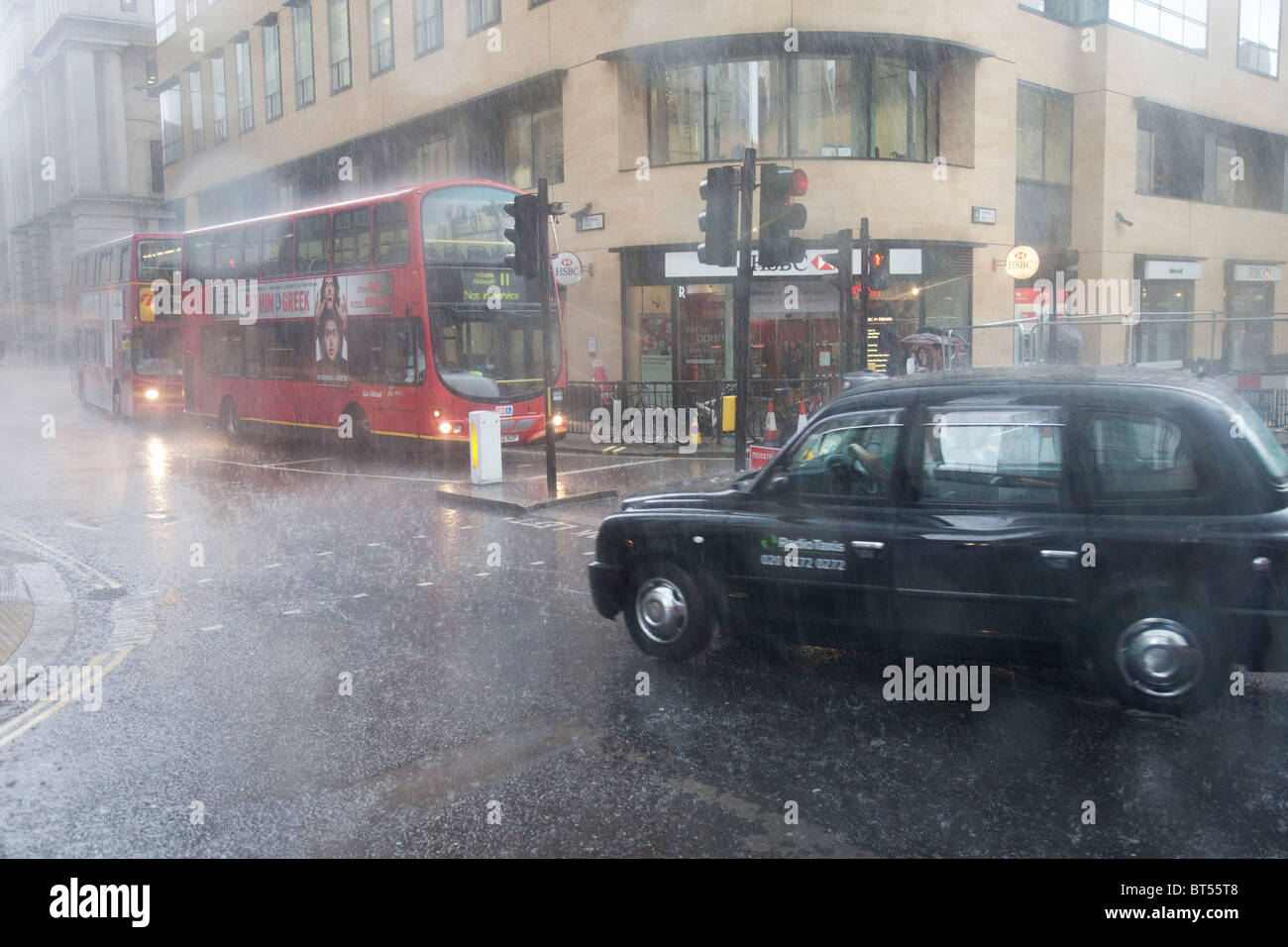London Transport in den schweren Regen auf London Wall. Ein schwarzes Taxi und roten Londoner Busse Stockfoto