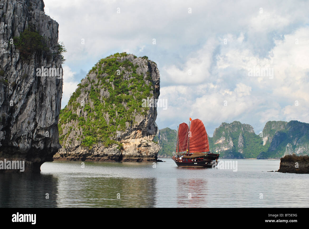 Dschunke mit roten Segel unter Kalksteininseln in Ha Long Bucht, Vietnam Stockfoto