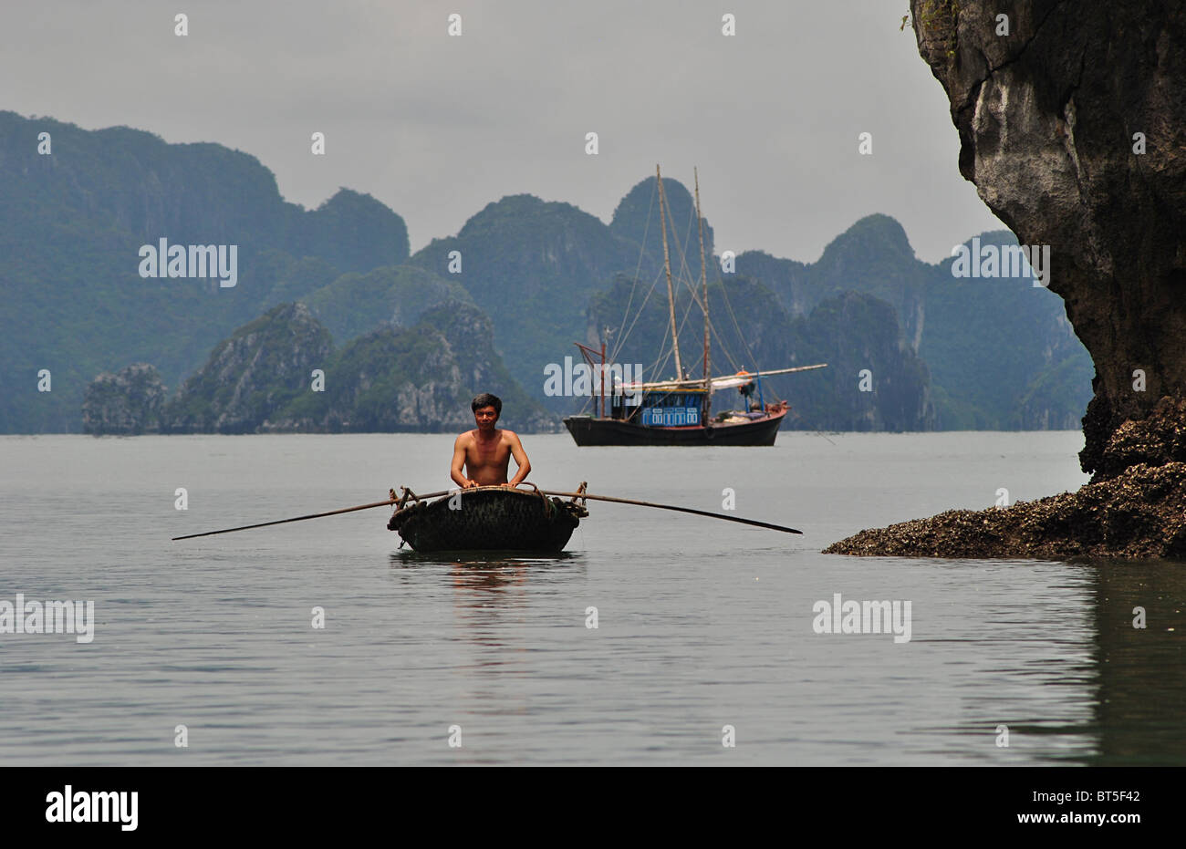 Trödel und Ruderboot in Halong Bucht, Vietnam Stockfoto