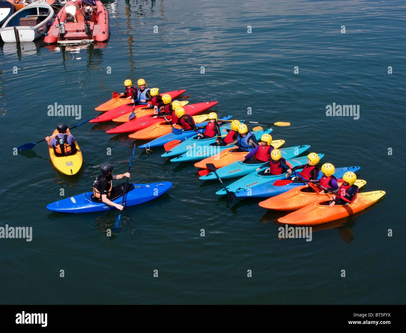 Linie von Kajaks für Trainingseinheit mit Studenten und Dozenten auf dem Wasser in Brixham Narbour, Devon, UK Stockfoto