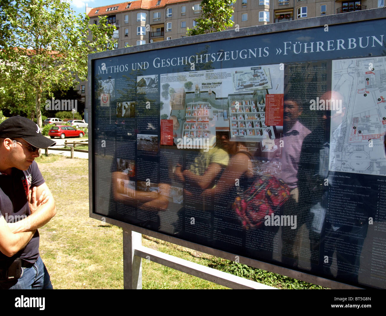 Reflexion der Besucher, die Prüfung einer Plakette markiert die Lage des Hitler Bunker, Berlin. Stockfoto